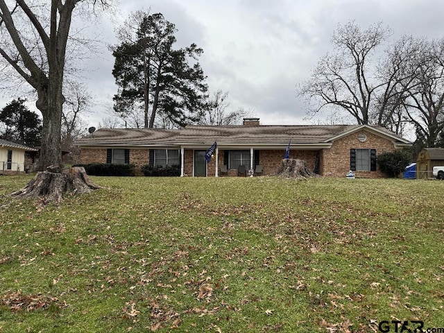 single story home with brick siding, a chimney, and a front yard