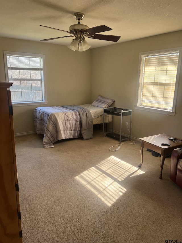 bedroom featuring ceiling fan, a textured ceiling, and carpet