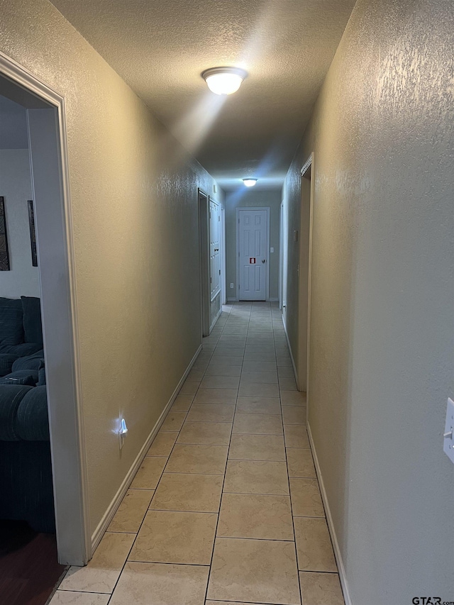 corridor featuring a textured ceiling and light tile patterned flooring