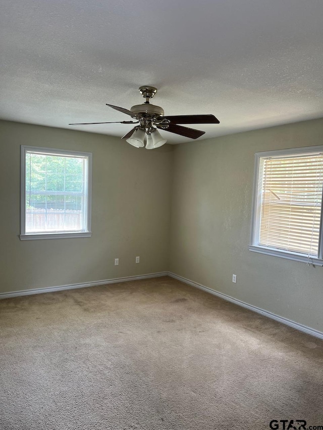 unfurnished room featuring carpet flooring, a ceiling fan, baseboards, and a textured ceiling