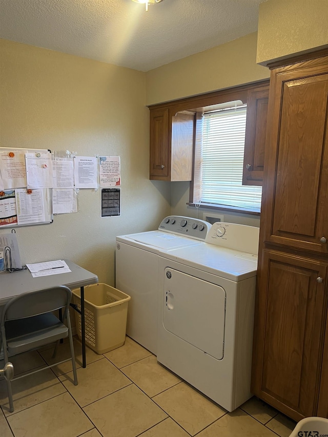 laundry room with cabinets, washing machine and dryer, light tile patterned floors, and a textured ceiling