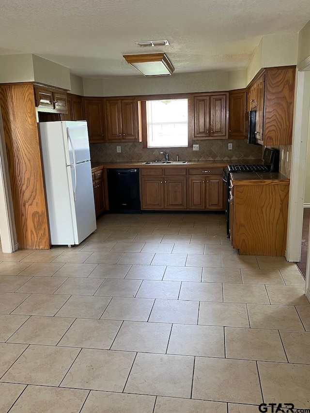kitchen with black appliances, a sink, tasteful backsplash, and brown cabinetry