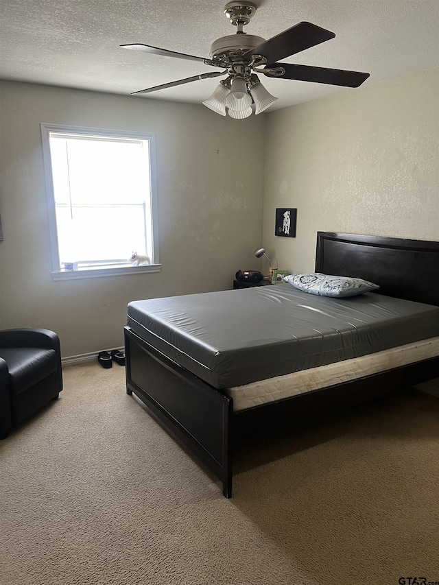 bedroom featuring light carpet, ceiling fan, and a textured ceiling