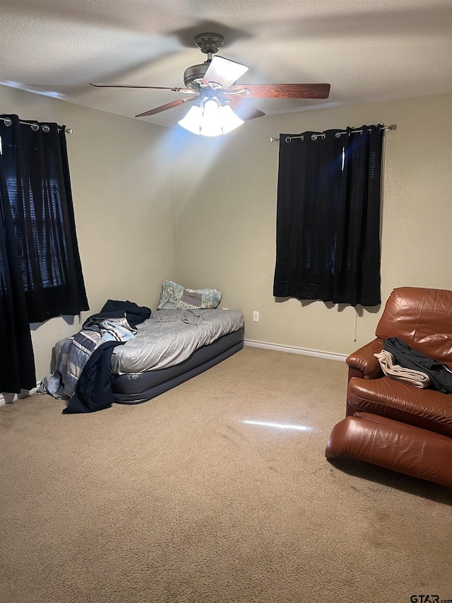 carpeted bedroom featuring ceiling fan and a textured ceiling