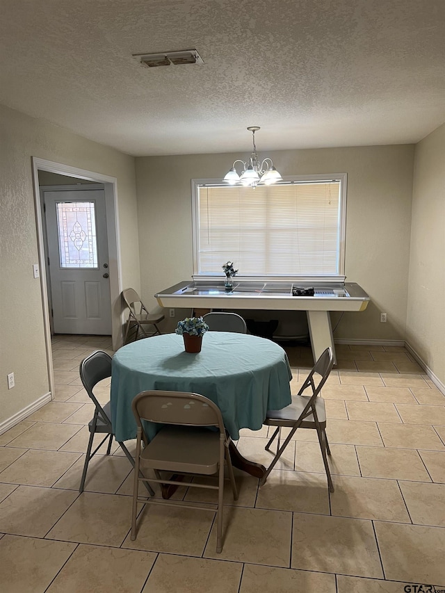 dining space featuring light tile patterned floors, a textured ceiling, and an inviting chandelier