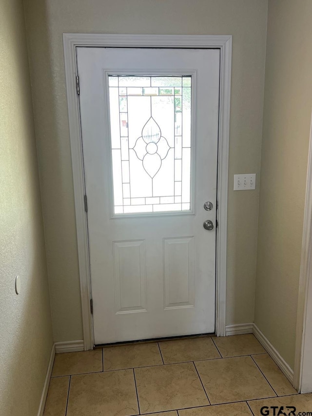 doorway to outside with baseboards and light tile patterned floors