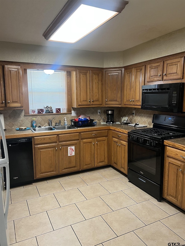 kitchen with tasteful backsplash, sink, light tile patterned floors, and black appliances