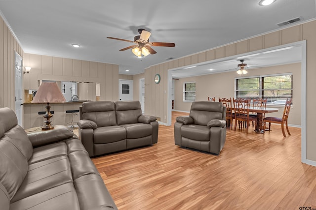 living room with ceiling fan, light hardwood / wood-style floors, and crown molding