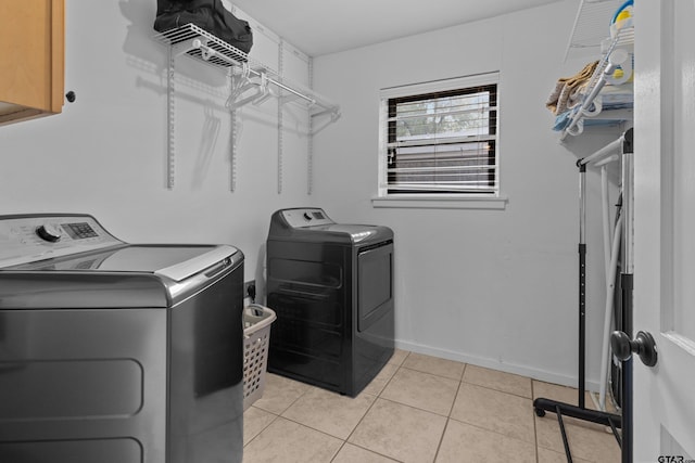 laundry area with cabinets, light tile patterned floors, and washer and clothes dryer