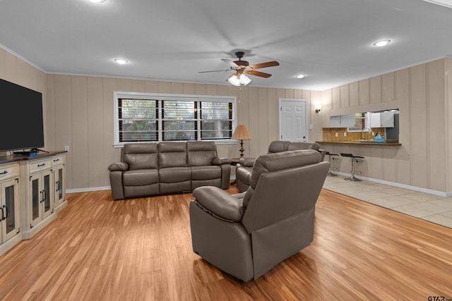 living room featuring ornamental molding, light hardwood / wood-style floors, and ceiling fan