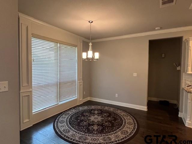 dining area with crown molding, dark wood-type flooring, and an inviting chandelier