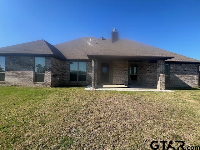 back of property with a yard and a patio