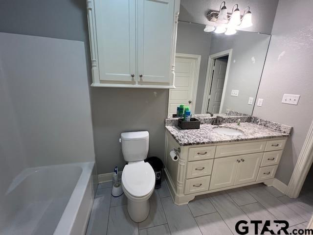 bathroom with a bath, vanity, and toilet