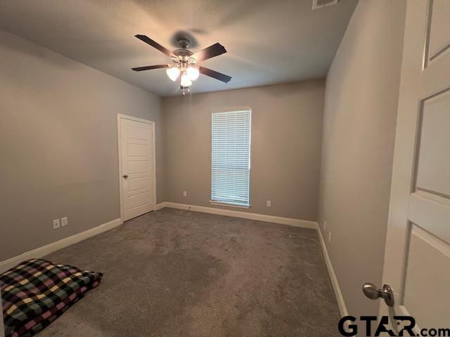 empty room featuring ceiling fan and dark carpet