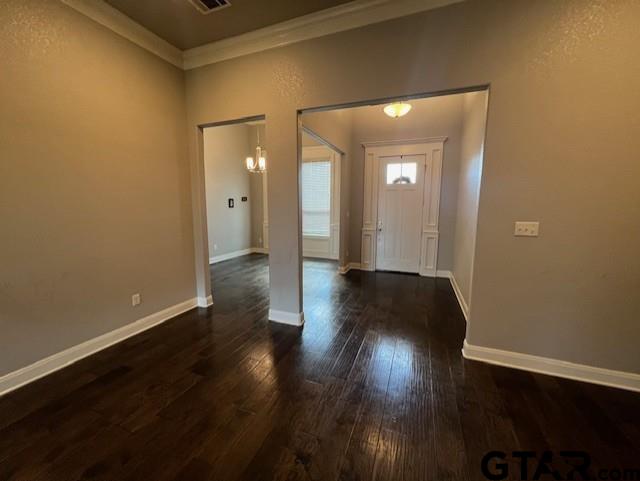 entryway with ornamental molding and dark wood-type flooring