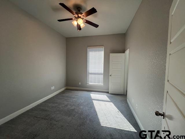 unfurnished room with ceiling fan and dark carpet