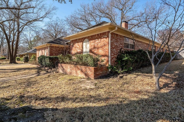 view of side of property featuring a chimney and brick siding