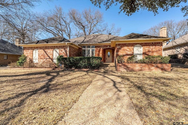 ranch-style house featuring brick siding and a chimney