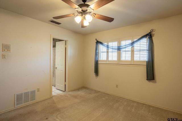 empty room featuring light carpet, ceiling fan, and visible vents