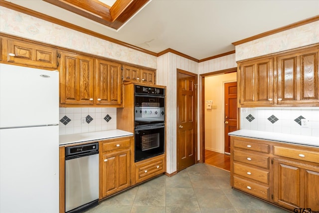 kitchen with dobule oven black, brown cabinetry, wallpapered walls, and freestanding refrigerator