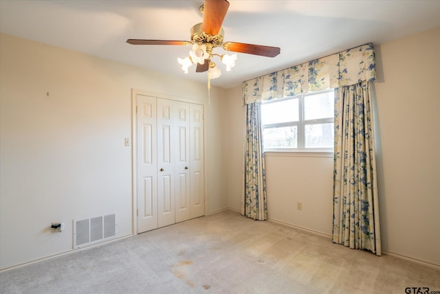 unfurnished bedroom featuring ceiling fan, a closet, carpet flooring, and visible vents