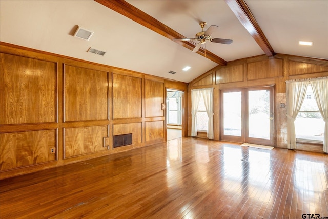 unfurnished living room with vaulted ceiling with beams, dark wood-style floors, visible vents, and wooden walls