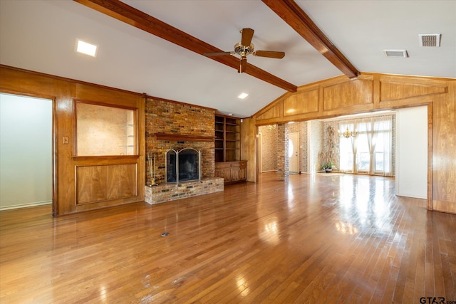 unfurnished living room featuring vaulted ceiling with beams, wood walls, a fireplace, and hardwood / wood-style floors