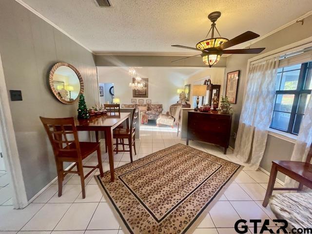 dining space featuring ceiling fan, light tile patterned flooring, a textured ceiling, and ornamental molding