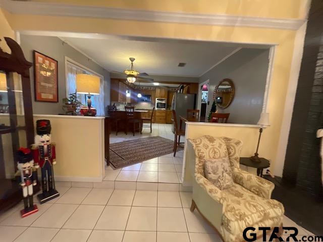 interior space with ceiling fan, crown molding, light tile patterned floors, and appliances with stainless steel finishes