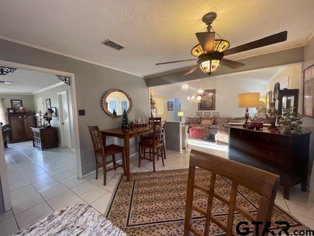 tiled dining space featuring crown molding, ceiling fan with notable chandelier, and a textured ceiling