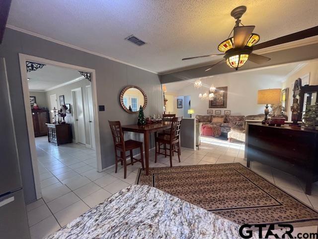 tiled dining area featuring ceiling fan with notable chandelier, ornamental molding, and a textured ceiling