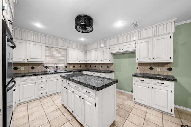 kitchen with a center island, white cabinetry, backsplash, visible vents, and a sink