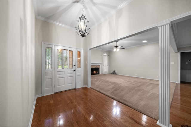 entryway featuring a warm lit fireplace, wood finished floors, crown molding, and ceiling fan with notable chandelier