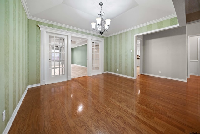 unfurnished room with a chandelier, baseboards, wallpapered walls, and wood finished floors