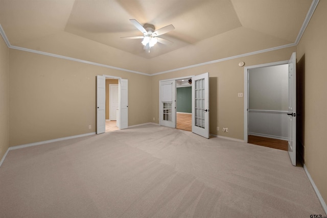 unfurnished bedroom with crown molding, baseboards, a raised ceiling, and light colored carpet