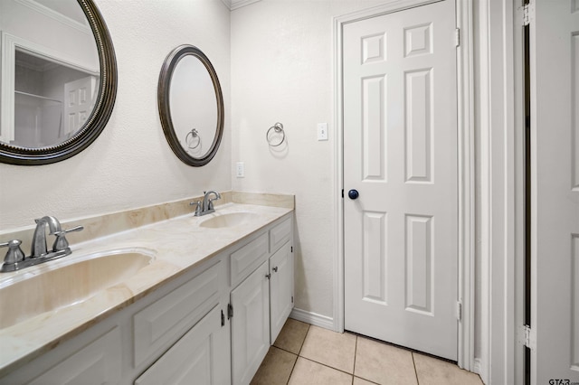 bathroom with a sink, tile patterned floors, double vanity, and baseboards