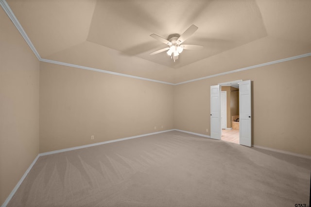 empty room with crown molding, ceiling fan, a tray ceiling, light colored carpet, and baseboards