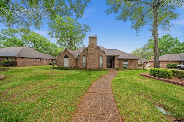 view of front facade featuring brick siding, a front lawn, a shingled roof, and a chimney