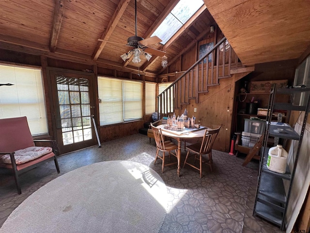 dining room with wood ceiling, wood walls, ceiling fan, and vaulted ceiling with skylight