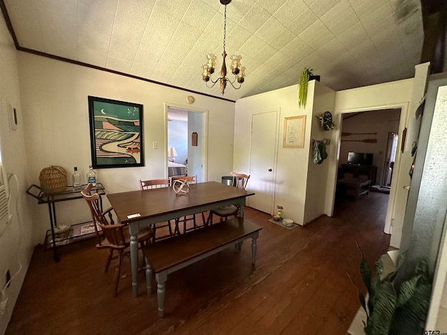 dining space featuring dark wood-type flooring, a chandelier, and vaulted ceiling