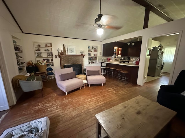 living room featuring a brick fireplace, hardwood / wood-style flooring, built in features, and ceiling fan