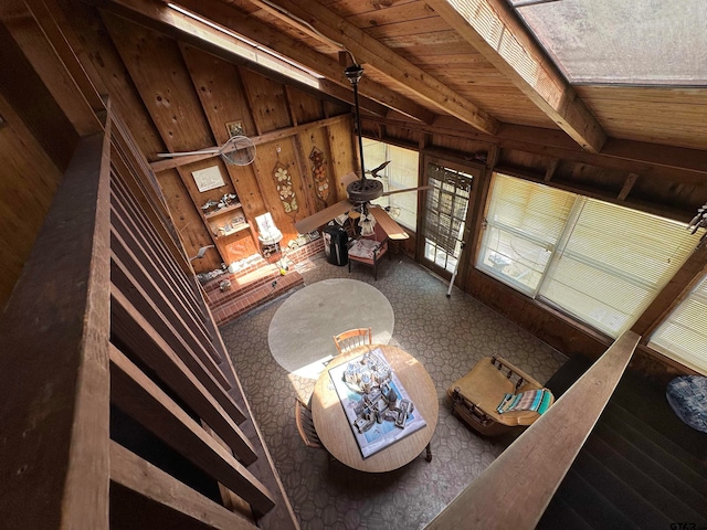 unfurnished living room featuring wood walls, ceiling fan, wooden ceiling, and vaulted ceiling with beams