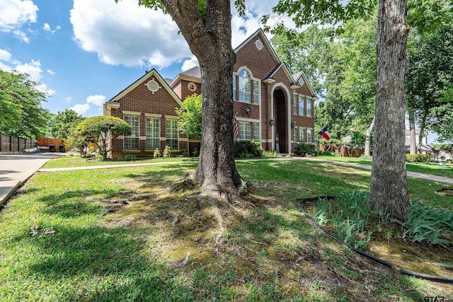 traditional-style house featuring fence, brick siding, and a front yard