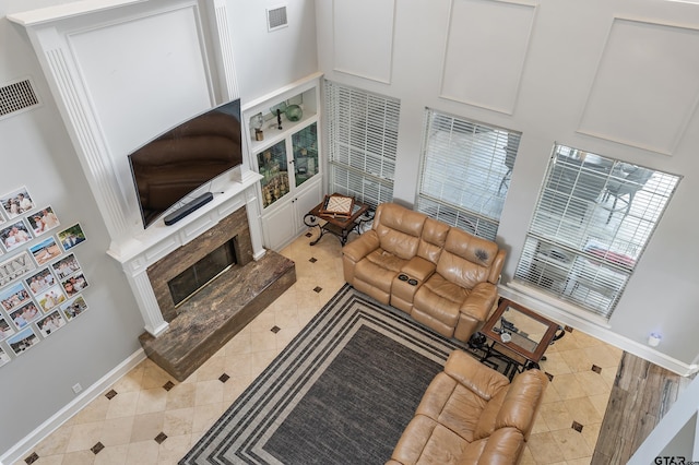 tiled living room featuring a high end fireplace, visible vents, and baseboards