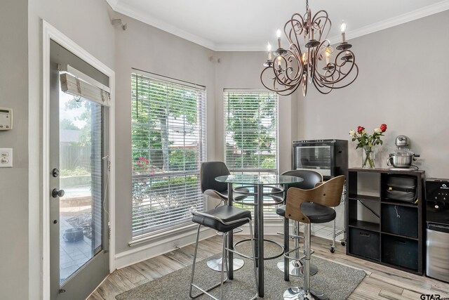 dining room featuring wood finished floors, crown molding, and a notable chandelier