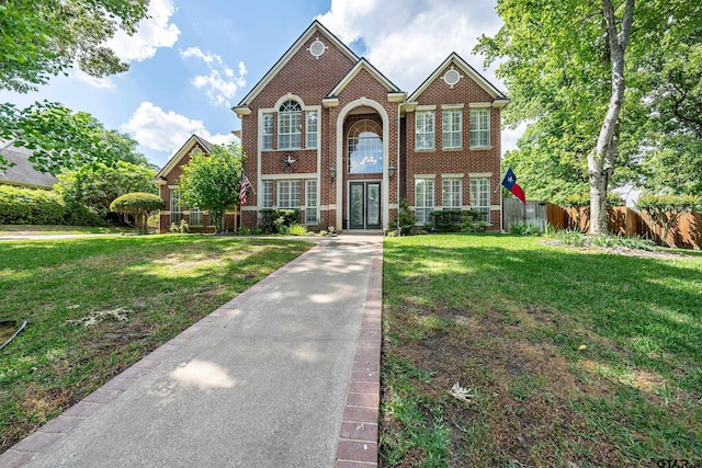 view of front of home featuring fence, brick siding, and a front yard