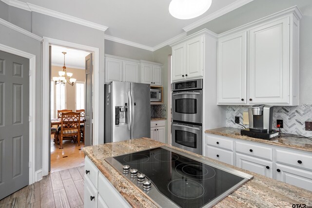 kitchen with stainless steel appliances, light wood-style flooring, a chandelier, and white cabinetry