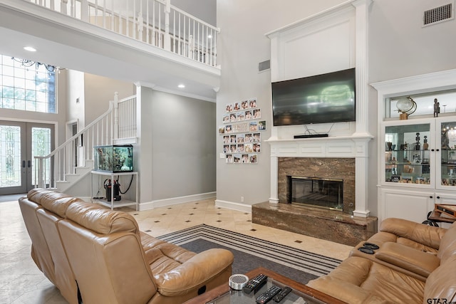 living area featuring stairway, a high ceiling, a fireplace, baseboards, and visible vents