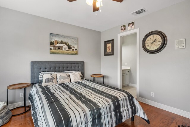 bedroom with wood finished floors, visible vents, connected bathroom, baseboards, and ceiling fan