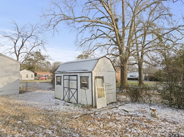 snow covered structure featuring a storage shed and an outdoor structure